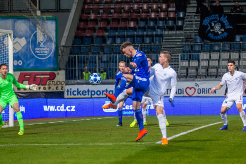 Martin Nešpor v těžké pozici před bránou Liberce bráněn na těsno, v pozadí vlajka mladých Chaotix Ultras z Liberce